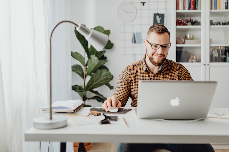 Pessoa com óculos e camisa quadriculada trabalhando no laptop