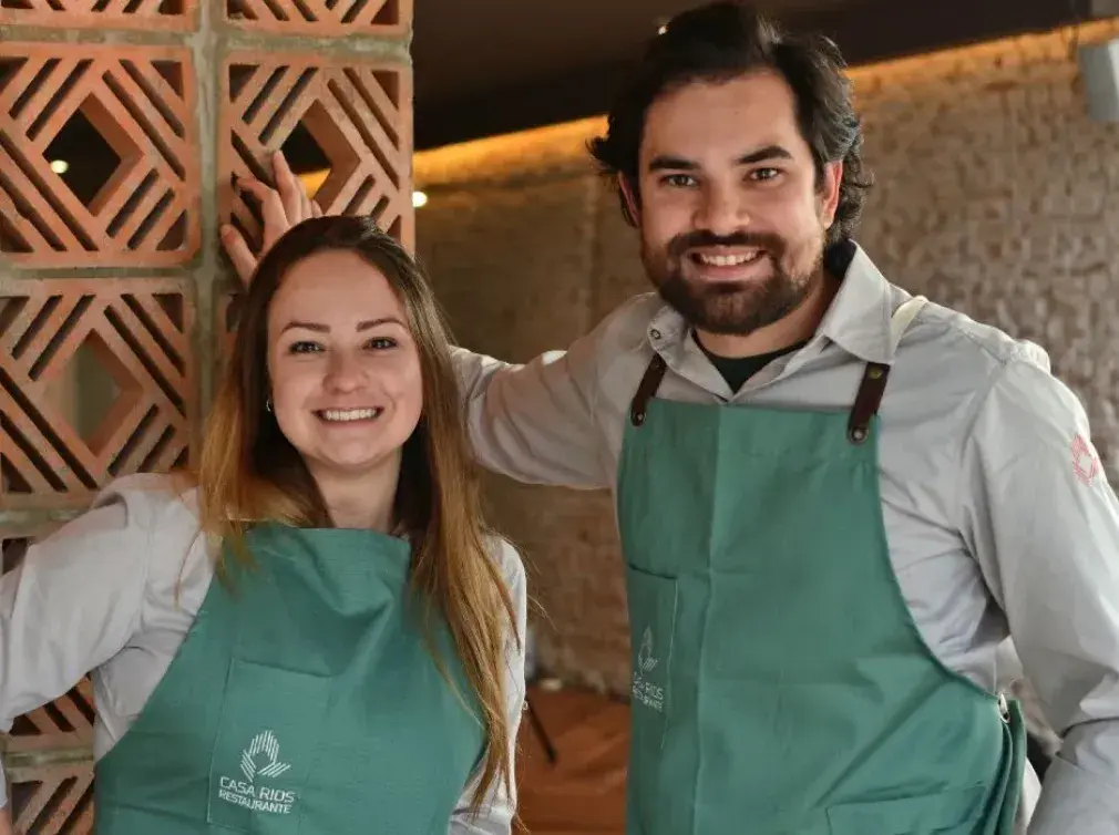 Chefs Rodrigo Aguair e Giovana Perrone lado a lado com avental de cozinheiro