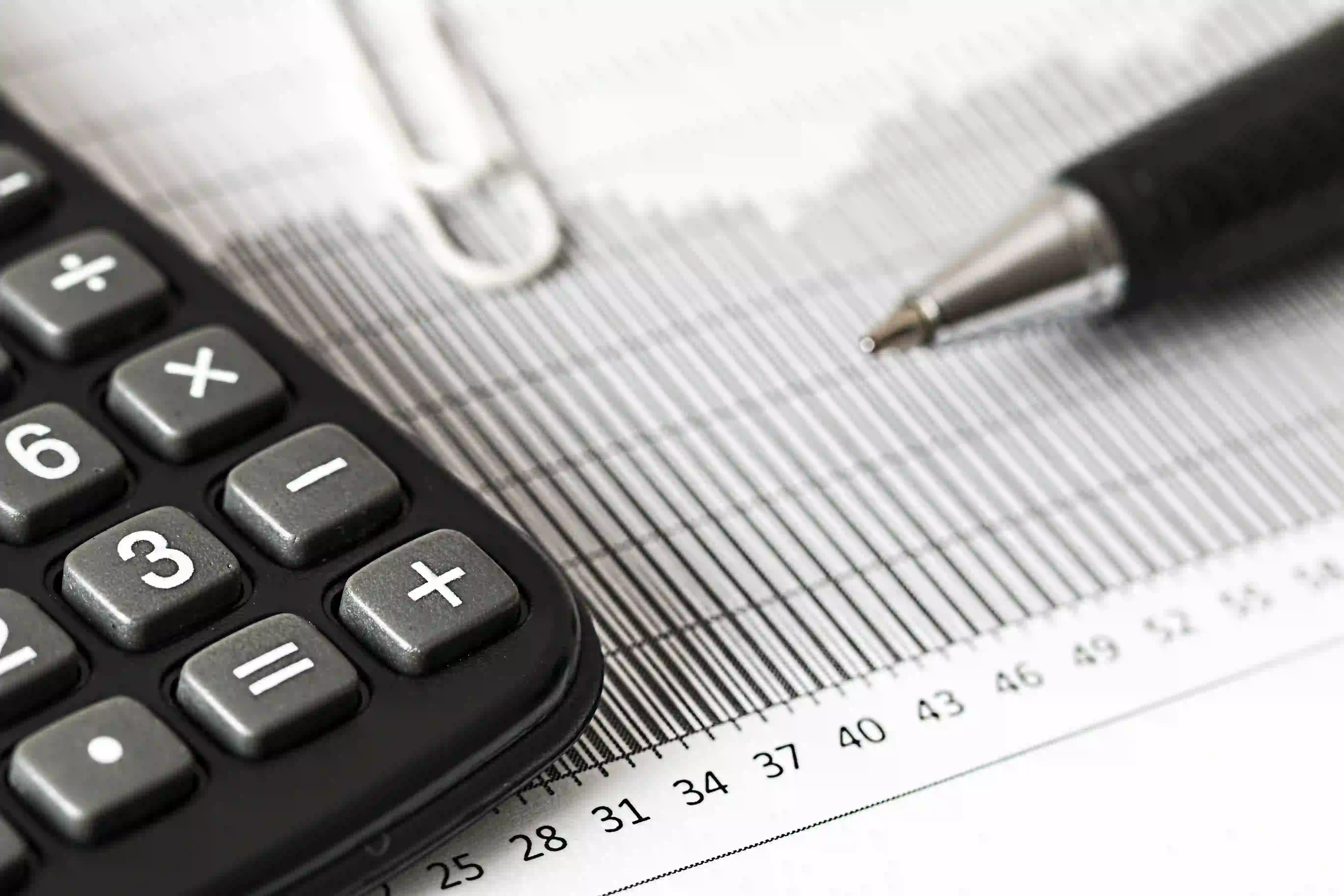  imagem de calculadora, papel e caneta em referência a declaração de imposto de renda 2024