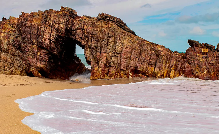 pedra furada na orla da praia como um portal
