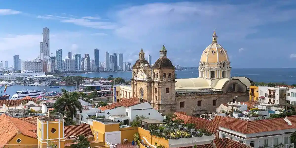imagem do alto de Cartagena com prédio antigo de igreja próximo a orla da praia e prédios modernos ao fundo.